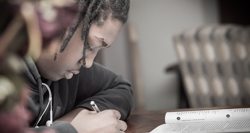 Teenage boy writing at a desk